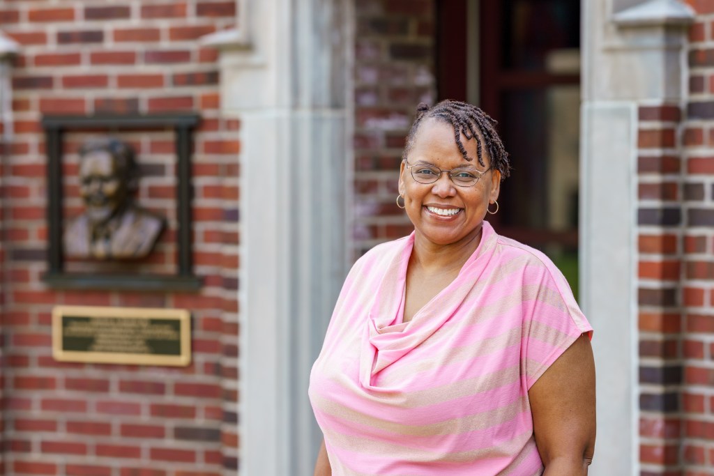 Dr. Carlotta Berry in front of the entrance to a brick building on campus