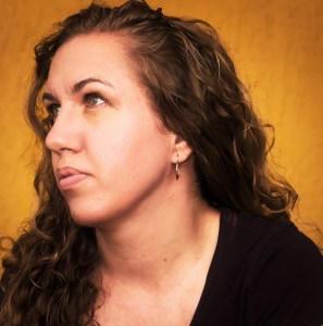 Headshot of Lisa Munro looking off into the distance with a gold background.