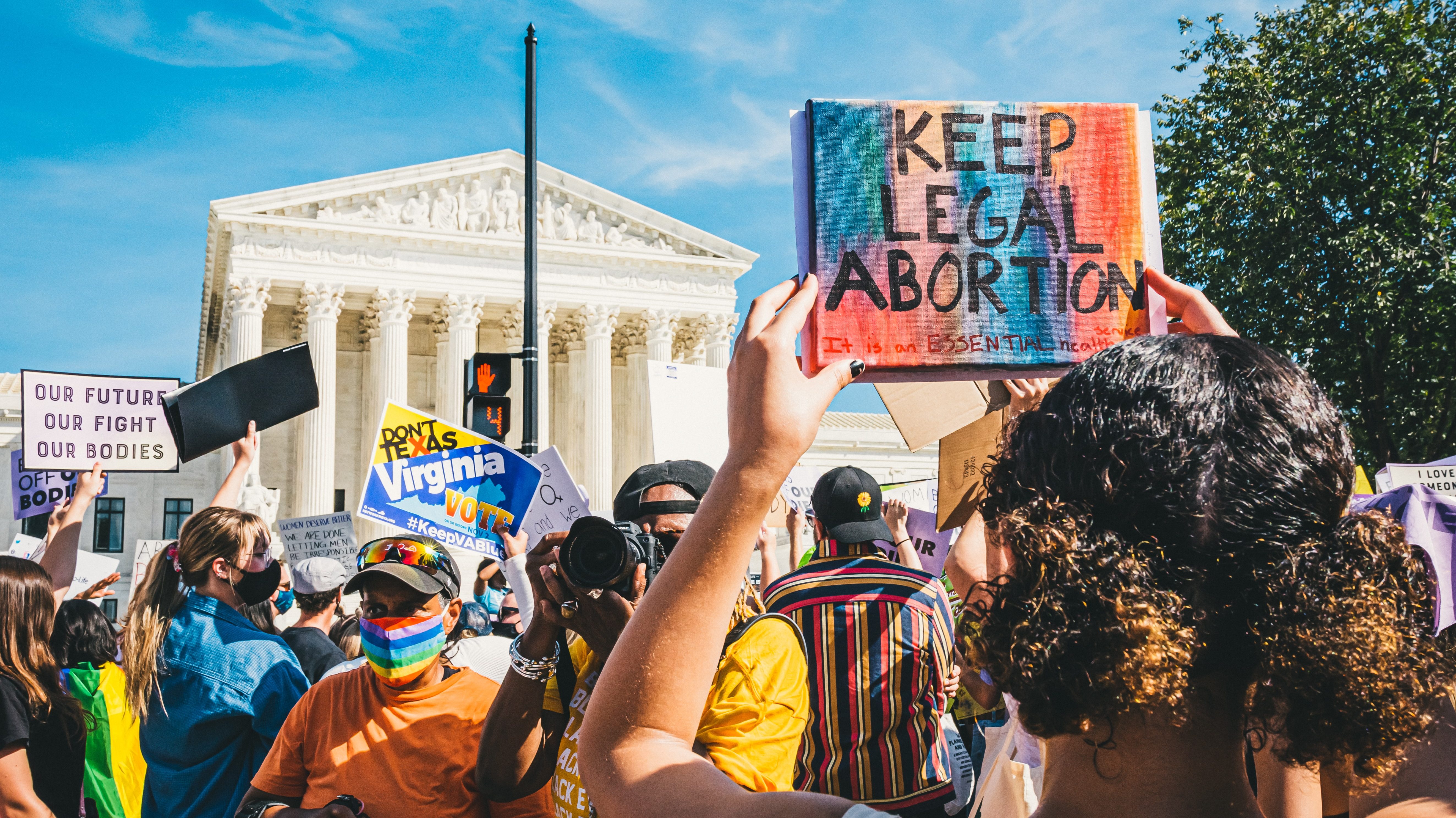 A women's rights protest in Washington DC in October 2021. Photo by Gayatri Malhotra. Protesters hold up signs that read 'keep abortion legal, it's an essential healthcare,' and 'our future our fight our bodies.'