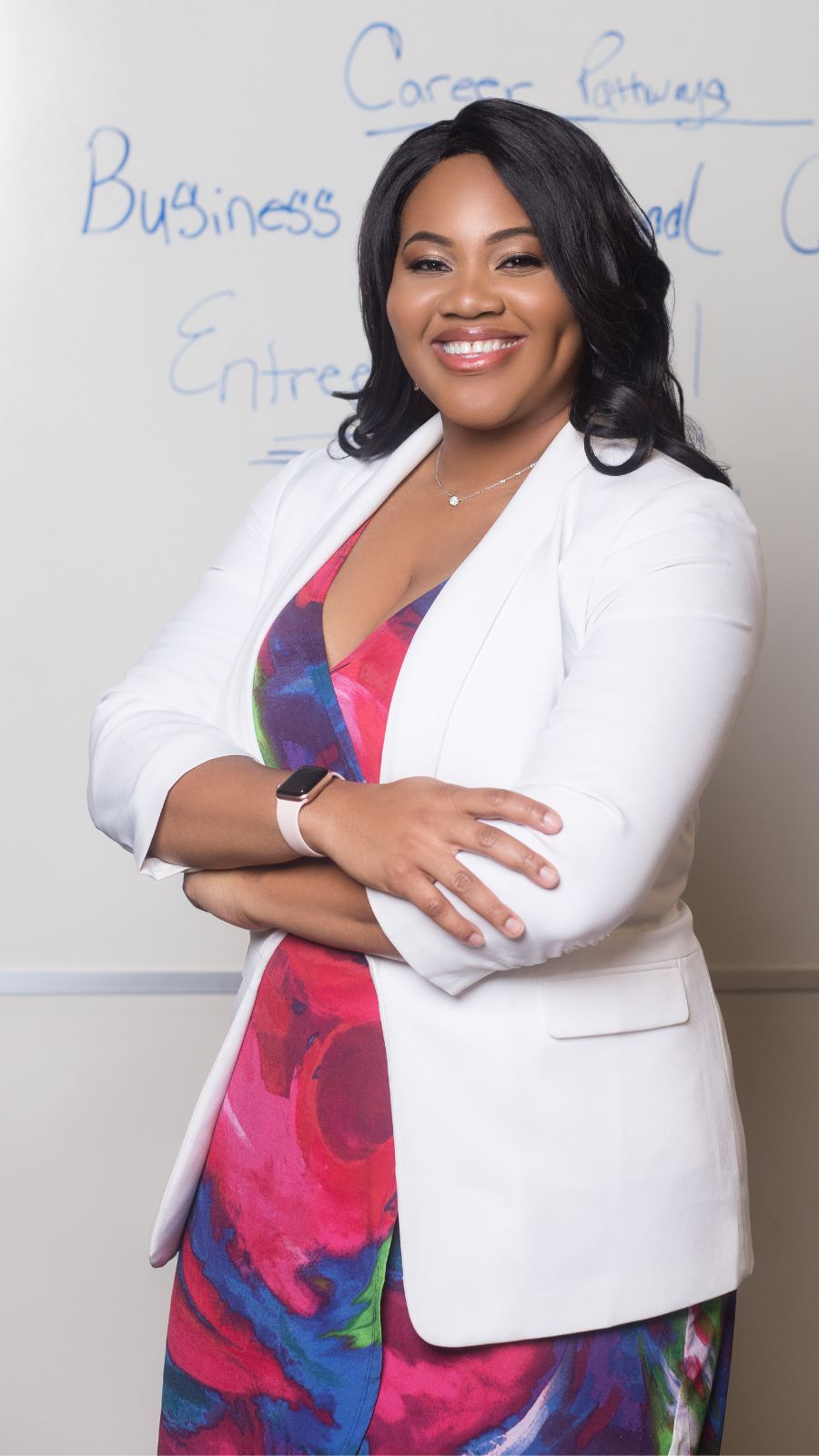 Chinasa Elue in front of a whiteboard wearing a white blazer and a patterned dress