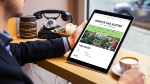 Man holds a tablet at a coffee shop overlooking the street with the personal website of Jennifer van Alstyne on the screen