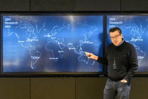 George Tulevski stands next to a world map 