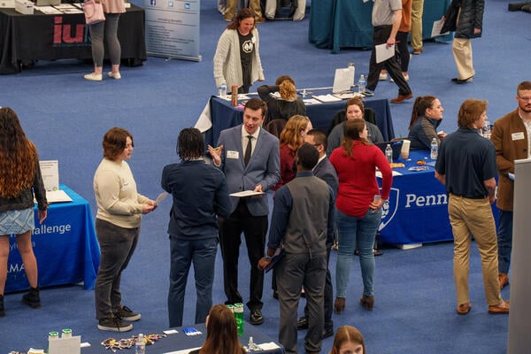 Students in professional dress interact with older adults at a career fair