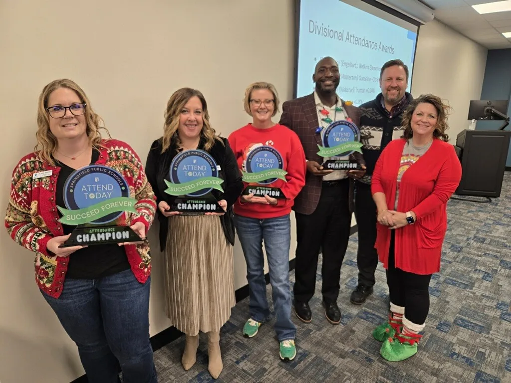 Six school administrators pose with attendance trophies in Missouri's Springfield Public Schools.