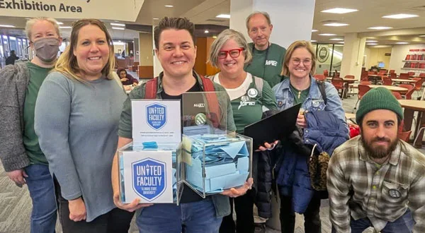 A group of smiling unionists, with one holding boxes of ballots