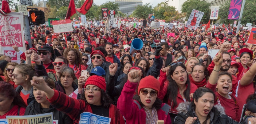 A massive gathering of workers with their fists up and chanting energetically.