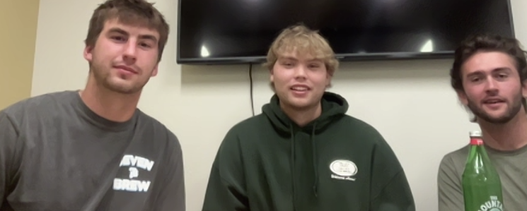 Three light-skinned young men, two wearing T-shirts and one in a hooded sweatshirt