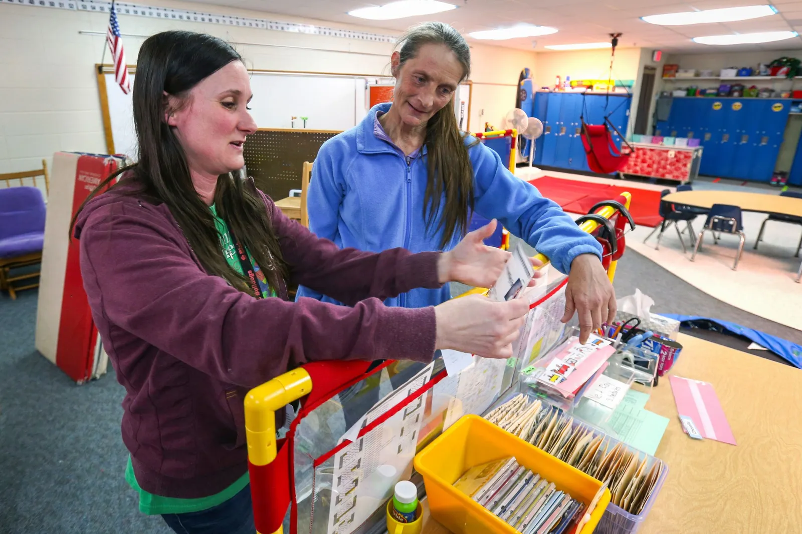 A teacher handles classroom materials with a paraprofessional in a school classroom.