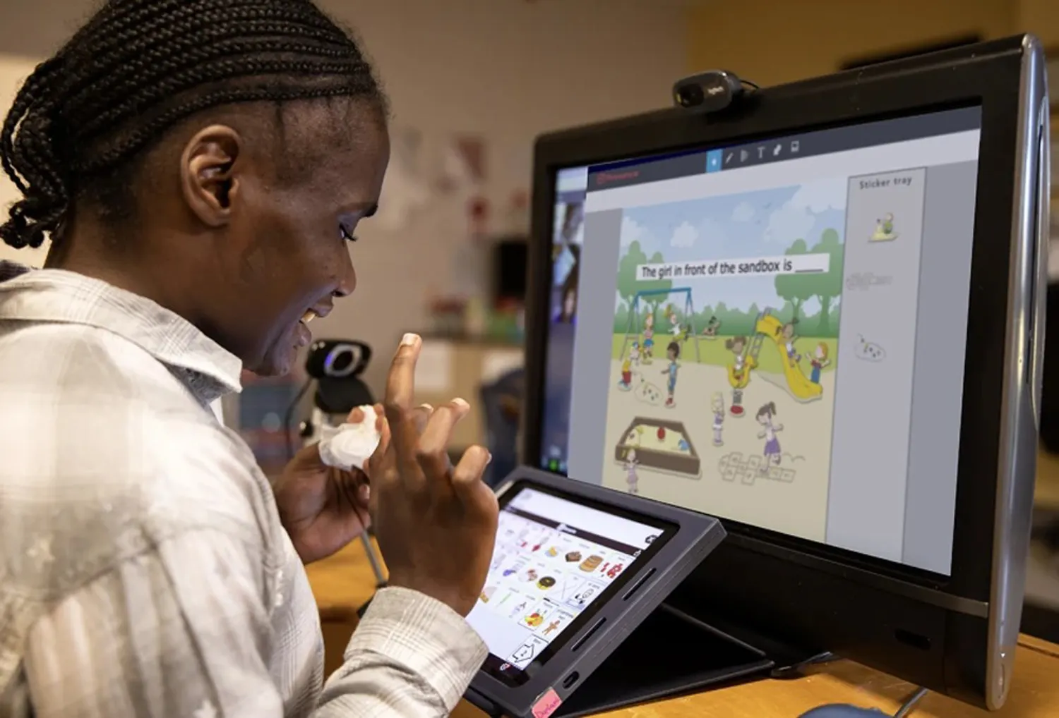 A student is seen from the side. They are looking at a screen in front of them and there is a monitor with a camera.