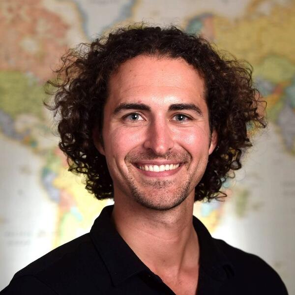 Michael Yankoski smiles for a headshot wearing a black collared shirt
