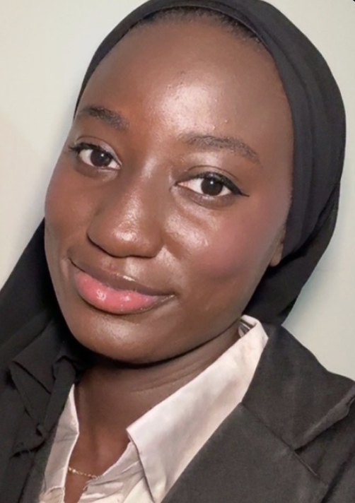 Ndeye Sarr, a young Black woman wearing a black head scarf and a pink blouse under a dark jacket.