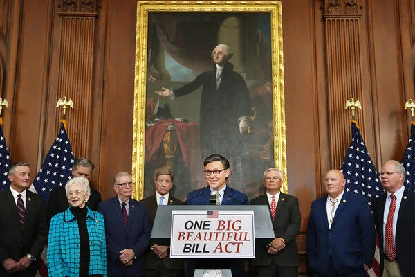 A group of Republican members of the House of Representatives, standing in front of a painting of George Washington and behind a podium that says "One Big Beautiful Bill Act."
